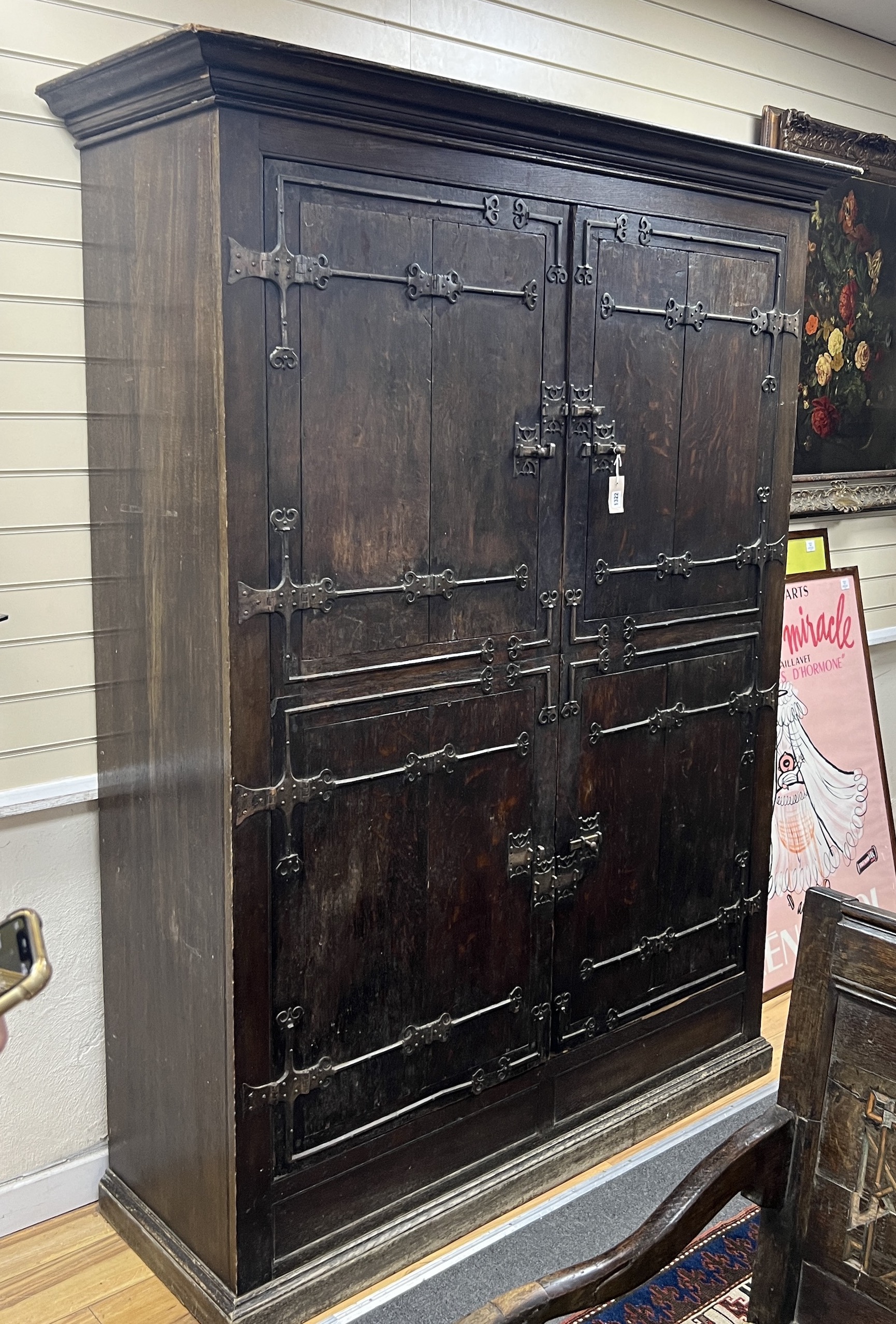 A pair of 16th century German or Netherlandish oak and wrought iron strapwork window shutters, later mounted on a cupboard, the moulded cornice above two pairs of hinged shutters, (previously bi-fold), mounted with elabo